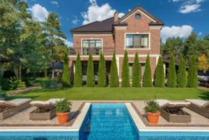 A house with modern outdoor space that includes a pool and green trees