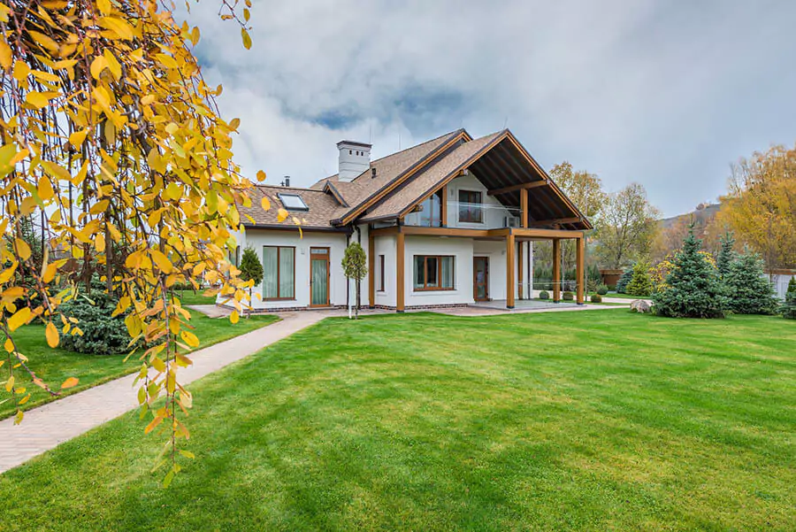 A beautiful house with a green lawn in fall autumn