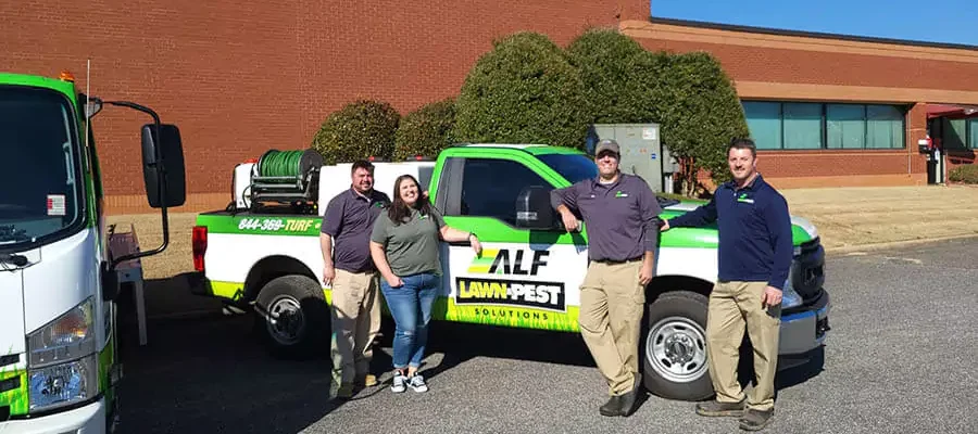ALF Lawn & Pest Solution team members stand in front of cars